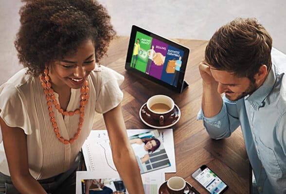  Imagen de un hombre y mujer reunidos tomando café, capacitándose con la Educación Amway en una tableta desde INA Virtual.